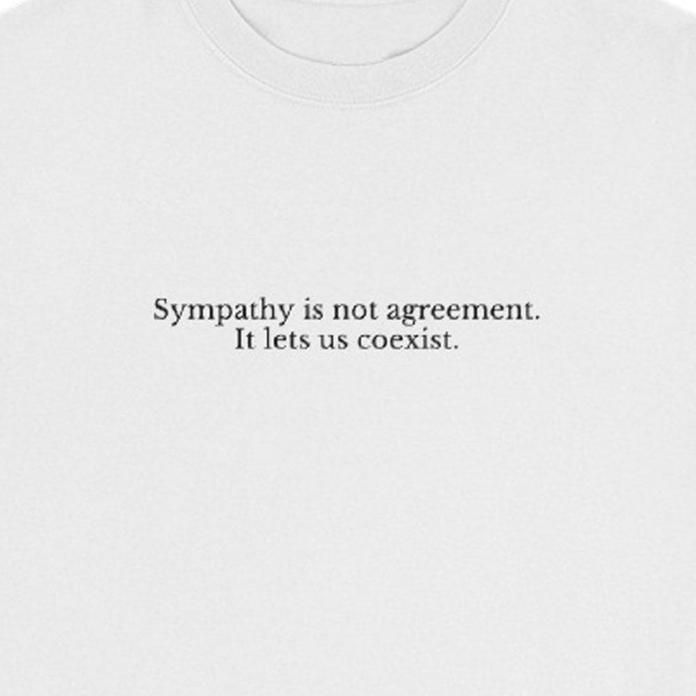 White t-shirt with black text 'Sympathy is not agreement. It lets us coexist' on a white background