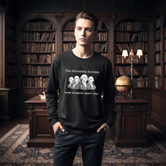 A man wearing a black long-sleeve graphic sweatshirt with a white print of the 'The Founding Fathers Were Worried About This' meme, standing in a dark, classic library with bookshelves.