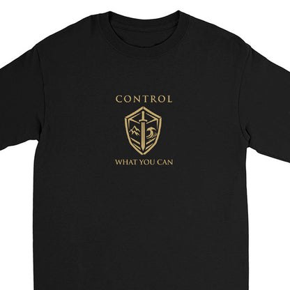 A black long-sleeve crewneck t-shirt featuring a gold graphic print on the chest with the text 'CONTROL WHAT YOU CAN' and a shield emblem.