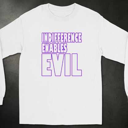 A white long-sleeve t-shirt with a bold graphic printed on the chest reading 'INDIFFERENCE ENABLES EVIL' in purple outline and solid lettering, displayed flat against a dark textured background.