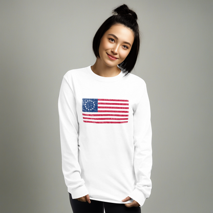Person wearing white long sleeve -shirt with a distressed image of the Betsy Ross Flag.