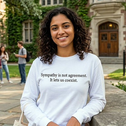 Woman wearing a long sleeve white tshirt with a philosophical quote,  'Sympathy is not agreement. It lets us coexist' standing outdoors on a college campus.