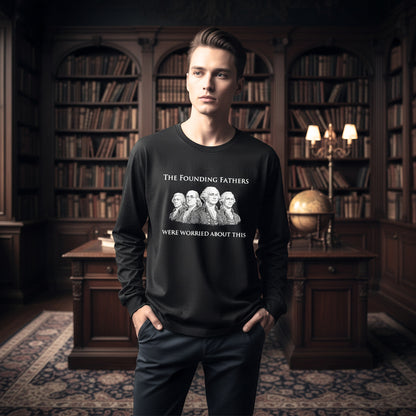 A man wearing a black long-sleeve graphic sweatshirt with a white print of the 'The Founding Fathers Were Worried About This' meme, standing in a dark, classic library with bookshelves.