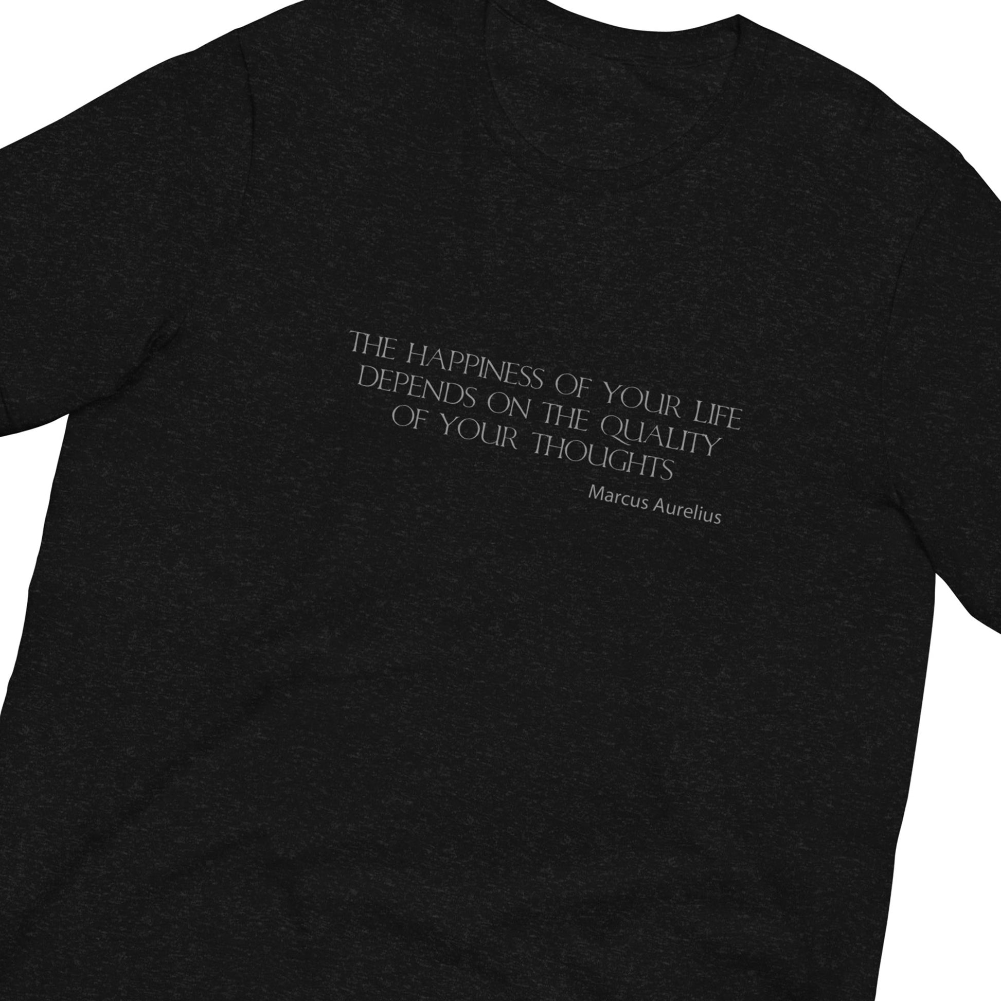 A close-up of a heather black t-shirt featuring a white printed quote by Marcus Aurelius on the chest.