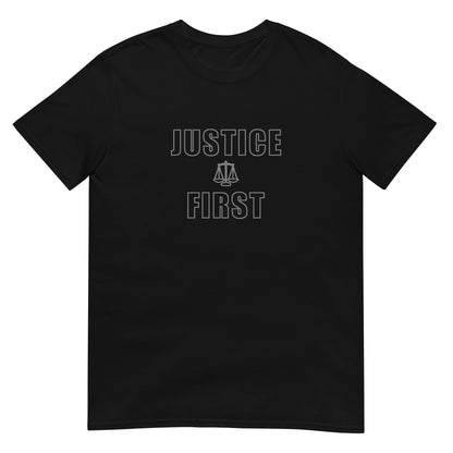 Black t-shirt with text outlined block letters "Justice First" with a line drawing of the scales of justice between the words in silver ink.